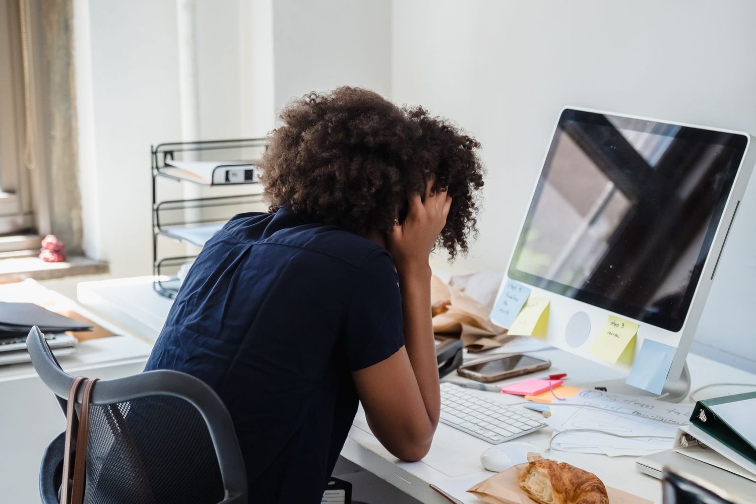 Trabajadora con la cabeza entre las manos frente a su escritorio en una oficina